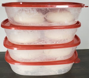 Pizza dough rising in plastic tubs with lids