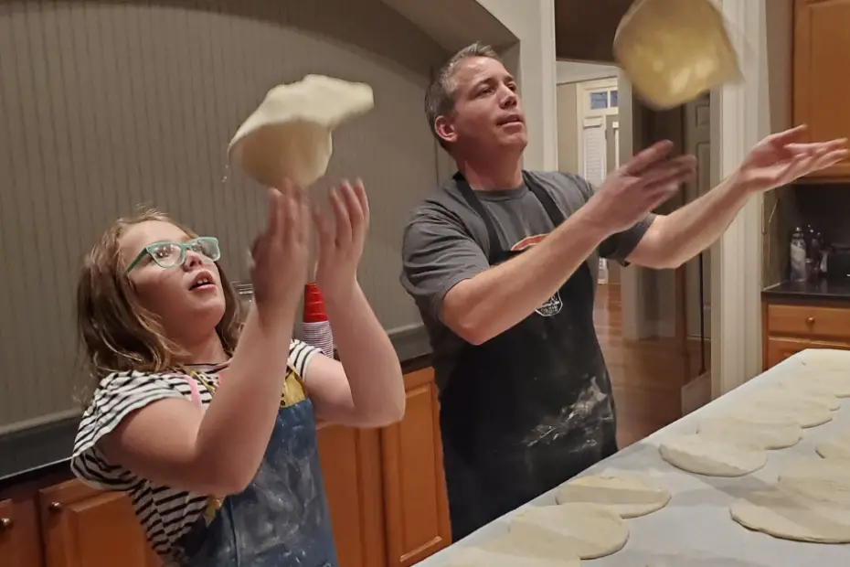 Dad and daughter making pizza dough and tossing it in the air