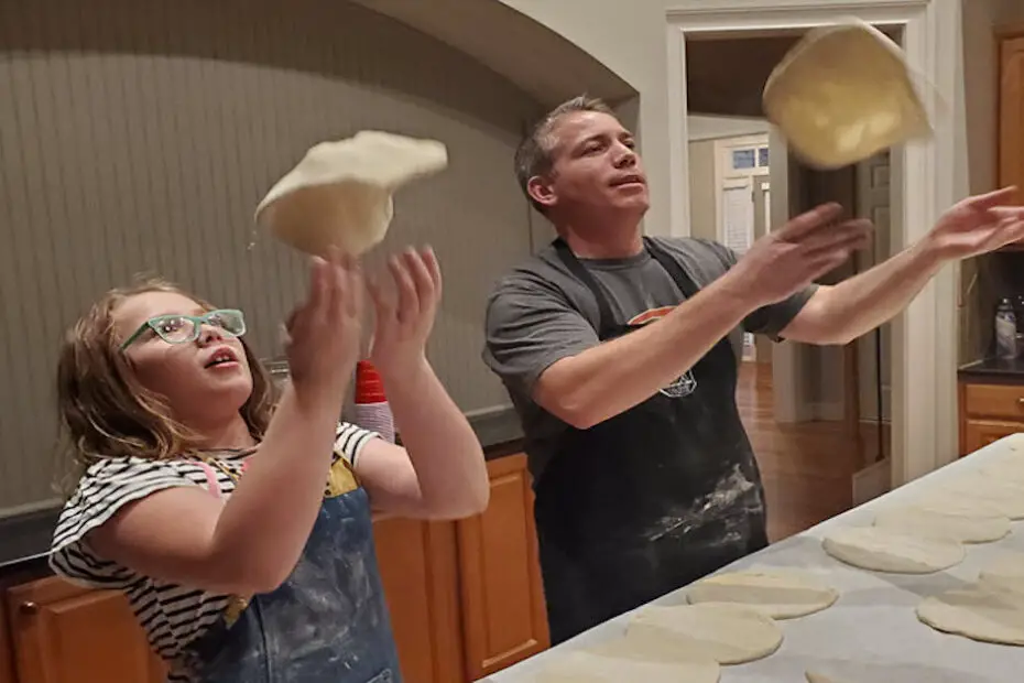 daddy and daughter tossing pizza dough