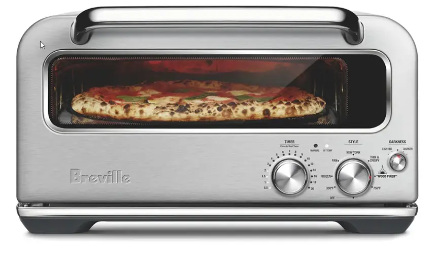 Breville Smart Oven Pizzaiolo electric pizza oven with pizza cooking inside.  Oven is set to Wood Fired and the pizza has a crust that looks like it was made in a wood fired pizza oven.